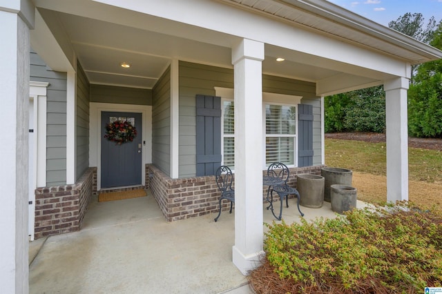 entrance to property featuring covered porch and brick siding