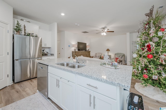 kitchen with light wood-type flooring, stainless steel appliances, ceiling fan, sink, and white cabinets