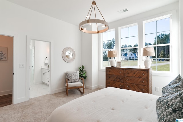 carpeted bedroom featuring a notable chandelier and ensuite bathroom