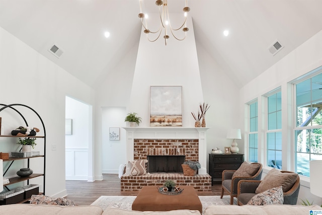 living room featuring hardwood / wood-style floors, a fireplace, high vaulted ceiling, and a chandelier