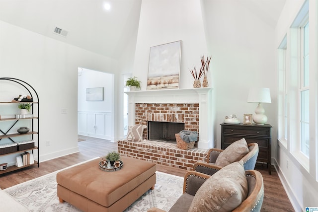 living room with a fireplace, high vaulted ceiling, and hardwood / wood-style floors