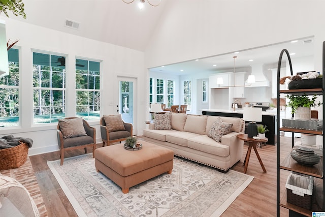 living room featuring a wealth of natural light, high vaulted ceiling, and light hardwood / wood-style floors