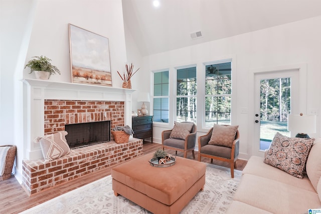 living room featuring a fireplace, light hardwood / wood-style flooring, and high vaulted ceiling