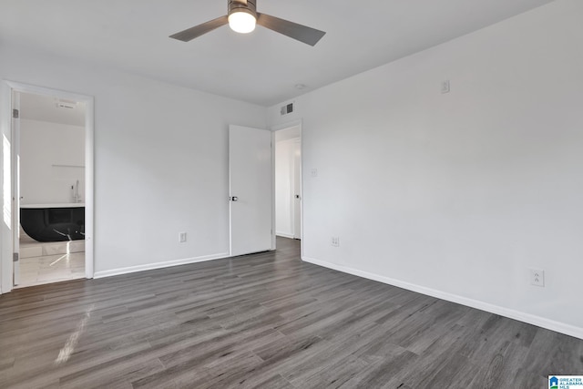 unfurnished bedroom featuring dark hardwood / wood-style floors, ensuite bath, and ceiling fan