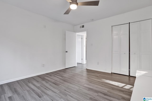 unfurnished bedroom with ceiling fan, a closet, and light wood-type flooring