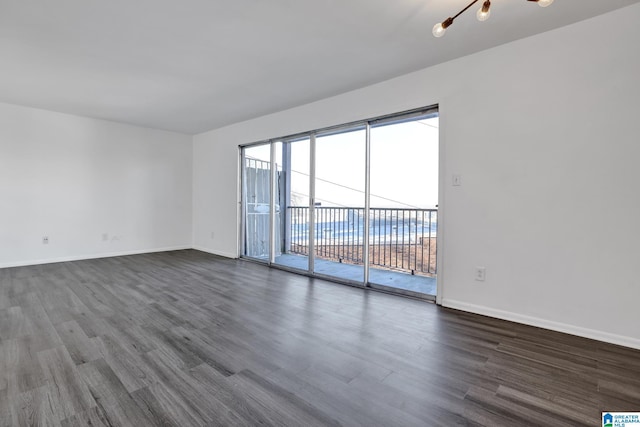 empty room with a notable chandelier and dark hardwood / wood-style floors