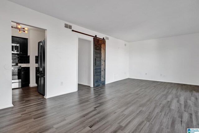 spare room featuring a barn door and dark hardwood / wood-style flooring