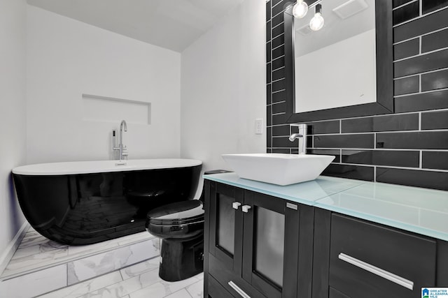 bathroom with decorative backsplash, vanity, a bath, and toilet