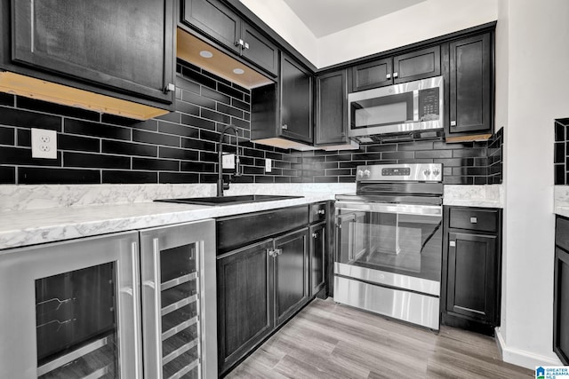 kitchen featuring sink, stainless steel appliances, tasteful backsplash, wine cooler, and light hardwood / wood-style floors