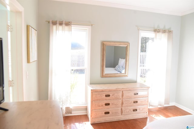 unfurnished bedroom featuring multiple windows, light hardwood / wood-style floors, and ornamental molding