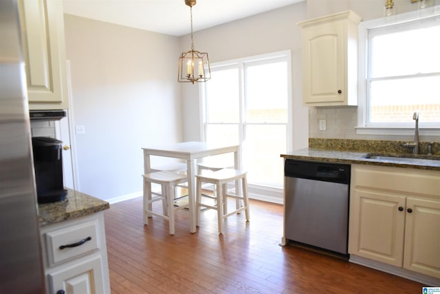 kitchen with pendant lighting, dishwasher, dark stone counters, sink, and dark hardwood / wood-style floors