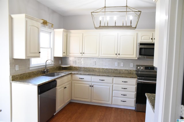 kitchen featuring backsplash, stainless steel appliances, dark wood-type flooring, sink, and hanging light fixtures