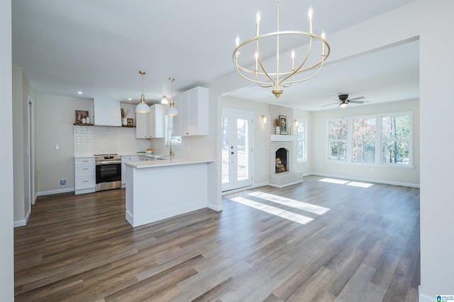 kitchen featuring dark hardwood / wood-style flooring, ceiling fan with notable chandelier, pendant lighting, electric range, and white cabinetry