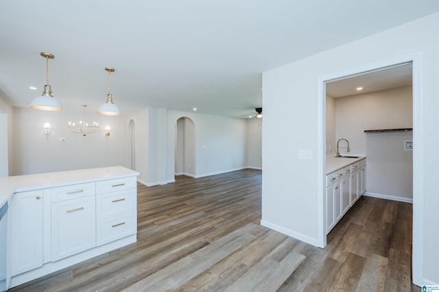 kitchen featuring ceiling fan with notable chandelier, white cabinets, decorative light fixtures, and light wood-type flooring