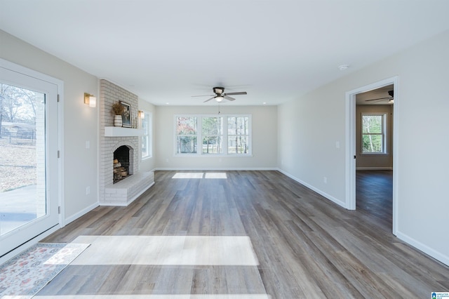 unfurnished living room with hardwood / wood-style floors, a brick fireplace, and ceiling fan