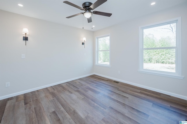 spare room with wood-type flooring, a wealth of natural light, and ceiling fan