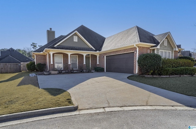 view of front of house featuring covered porch, a garage, and a front lawn