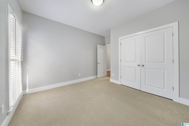 unfurnished bedroom with a closet and light colored carpet