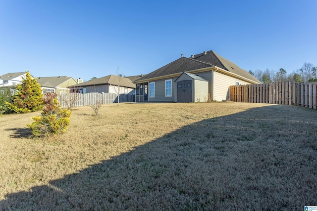 rear view of property featuring a storage unit and a yard