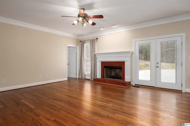 unfurnished living room with french doors, crown molding, ceiling fan, dark hardwood / wood-style floors, and a fireplace