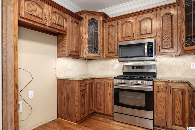 kitchen featuring light hardwood / wood-style floors, light stone countertops, and appliances with stainless steel finishes