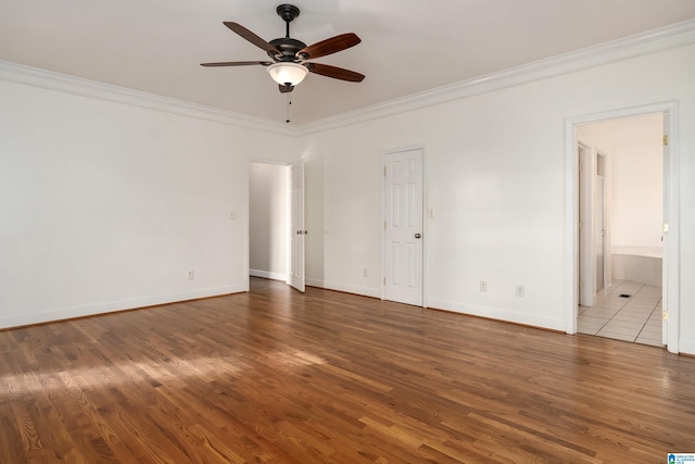 spare room featuring dark wood-type flooring, ceiling fan, and crown molding