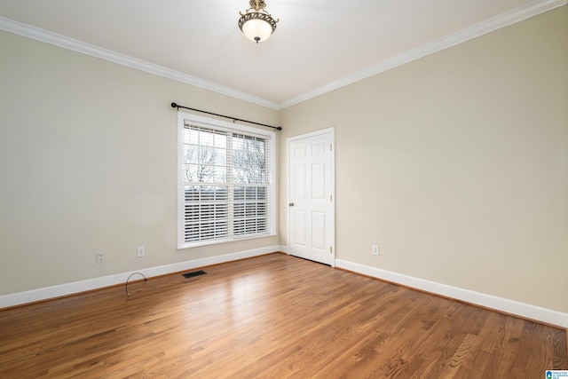 empty room with hardwood / wood-style flooring and crown molding