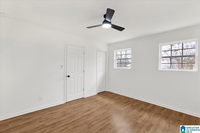 unfurnished bedroom with hardwood / wood-style flooring, ceiling fan, and two closets