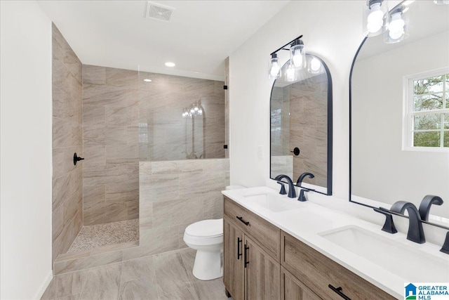 bathroom with toilet, vanity, and tiled shower