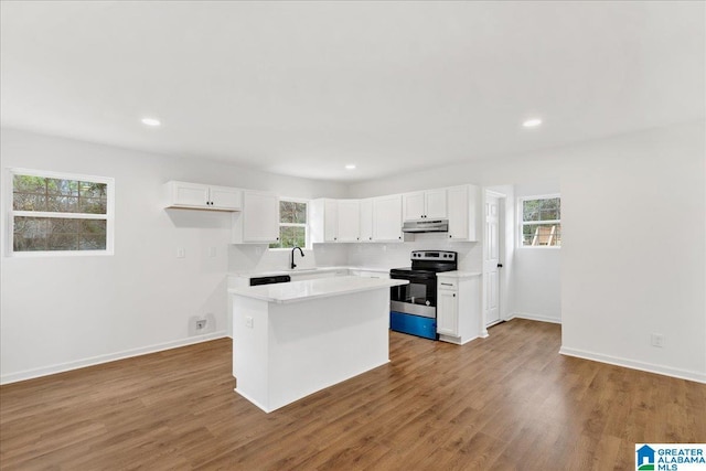 kitchen with stainless steel range with electric stovetop, a center island, white cabinets, and sink