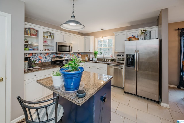 kitchen featuring a center island, stainless steel appliances, light tile patterned floors, pendant lighting, and white cabinets