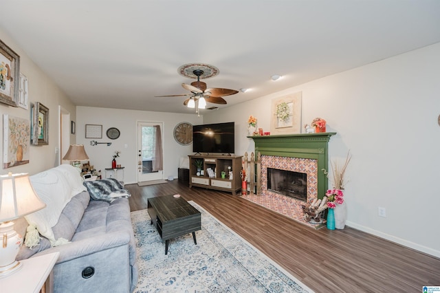 living room featuring a tiled fireplace, ceiling fan, and hardwood / wood-style floors