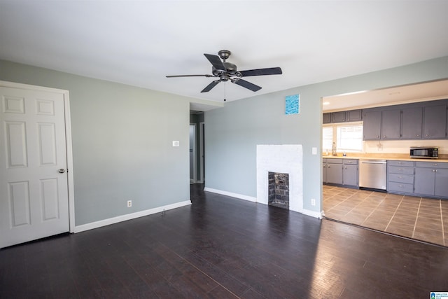 unfurnished living room featuring ceiling fan, a fireplace, wood-type flooring, and sink