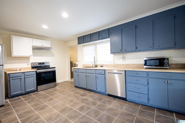 kitchen with appliances with stainless steel finishes, white cabinetry, blue cabinets, and sink