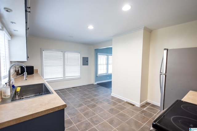 kitchen featuring electric panel, ornamental molding, sink, and stainless steel refrigerator