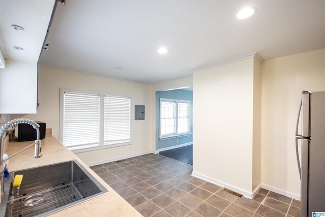 kitchen with stainless steel refrigerator, sink, electric panel, dark tile patterned flooring, and ornamental molding