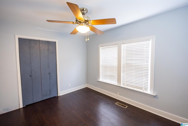 unfurnished bedroom with ceiling fan, dark hardwood / wood-style floors, and a closet