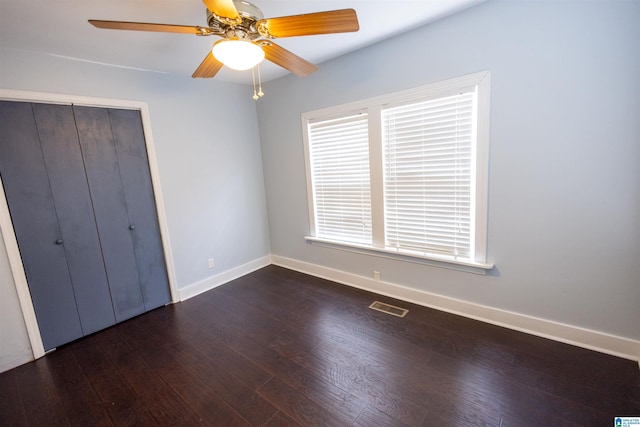 unfurnished bedroom with ceiling fan, dark wood-type flooring, and a closet