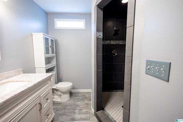 bathroom featuring tiled shower, vanity, and toilet