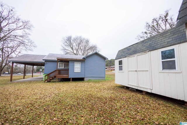 back of property with a carport and a storage shed