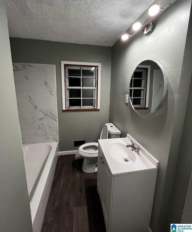 bathroom featuring a bathtub, toilet, a textured ceiling, and vanity