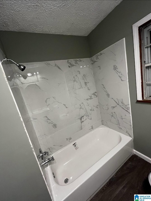 bathroom featuring hardwood / wood-style flooring, tub / shower combination, and a textured ceiling