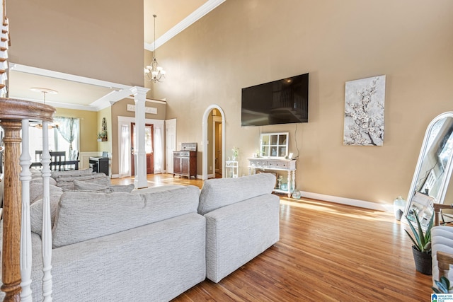 living room featuring decorative columns, crown molding, hardwood / wood-style floors, and an inviting chandelier