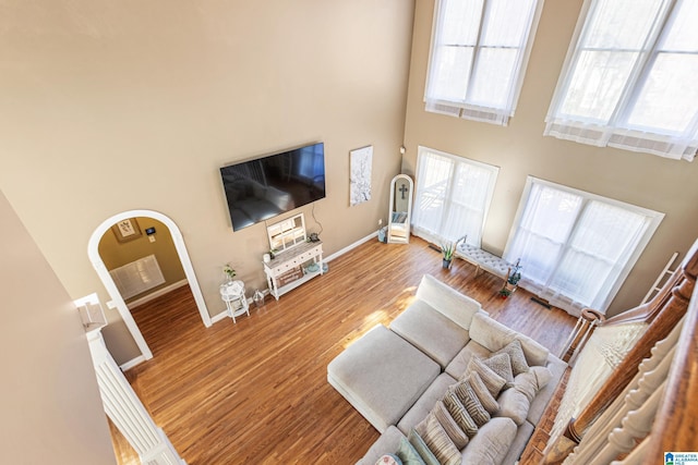 living room with a towering ceiling and wood-type flooring