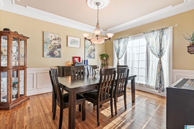 dining space featuring crown molding, light hardwood / wood-style floors, and an inviting chandelier