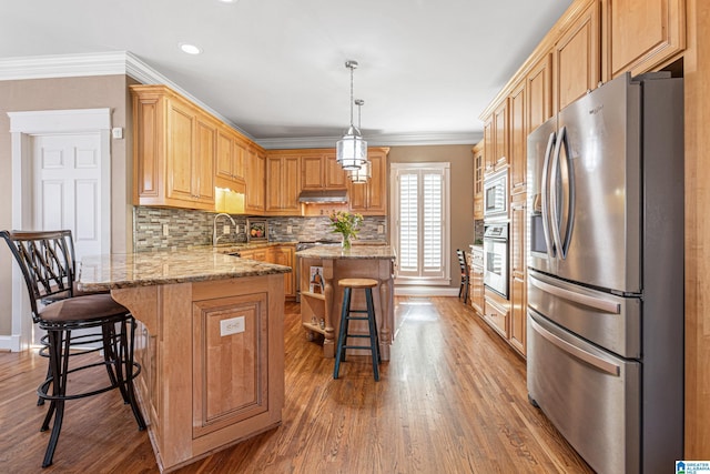 kitchen featuring a breakfast bar, a center island, stainless steel appliances, and decorative light fixtures