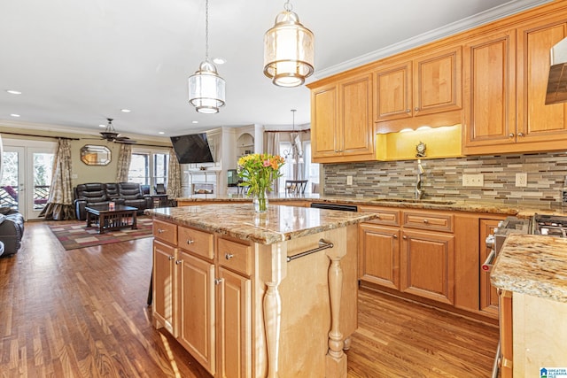 kitchen featuring ceiling fan, crown molding, sink, a kitchen island, and hanging light fixtures