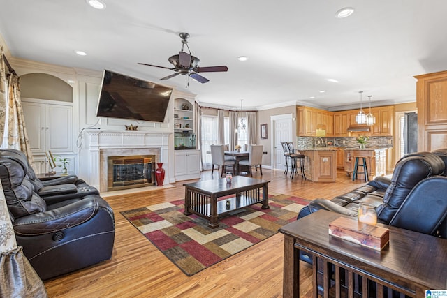 living room featuring light wood-type flooring, ceiling fan, and crown molding