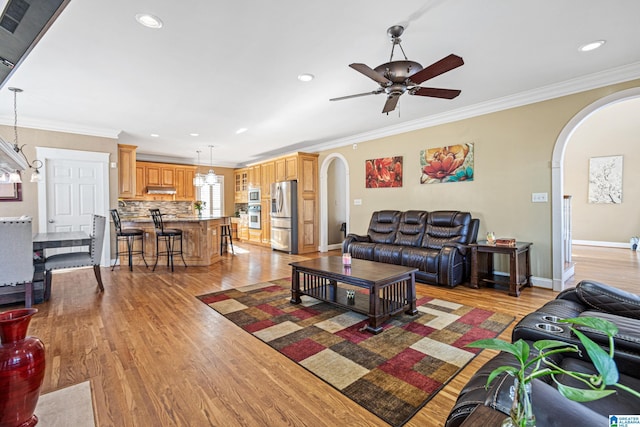 living room with crown molding, light hardwood / wood-style flooring, and ceiling fan