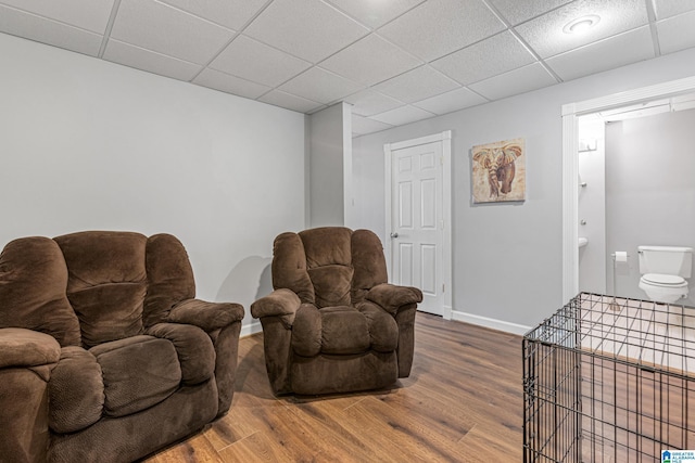 living room with wood-type flooring and a drop ceiling